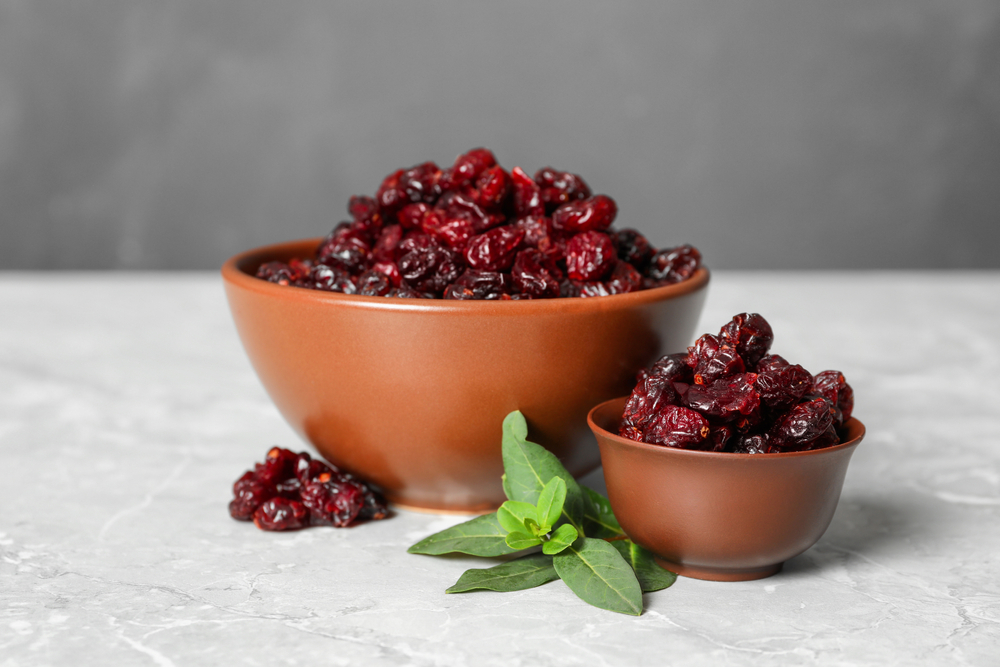 Tasty,Dried,Cranberries,And,Leaves,In,Bowls,On,Grey,Table