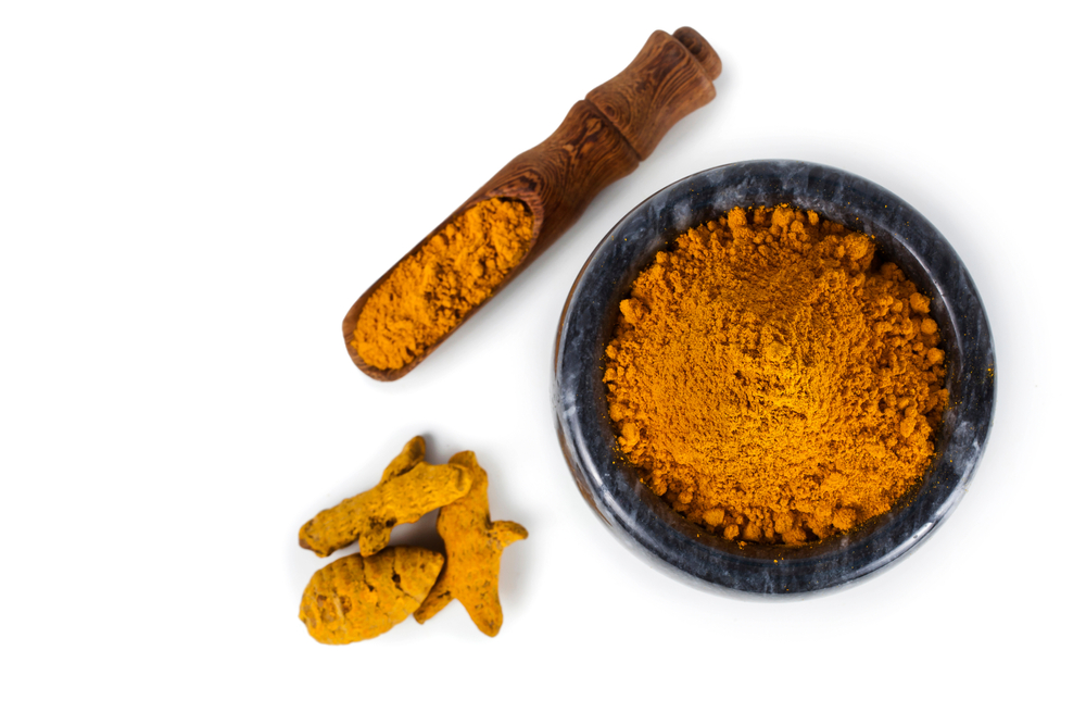 Turmeric,Powder,Spice,Heap,In,A,Black,Stone,Bowl,With