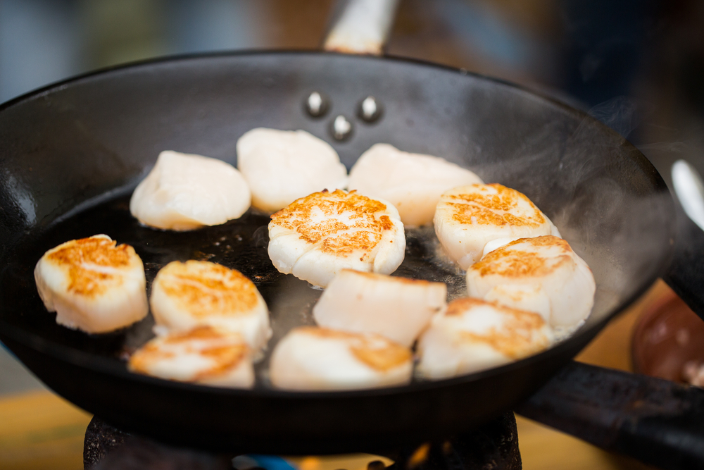 close up of scallops frying in cast iron pan