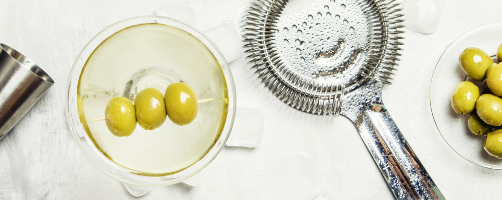 Classic alcoholic cocktail with dry vermouth and green olives, b
