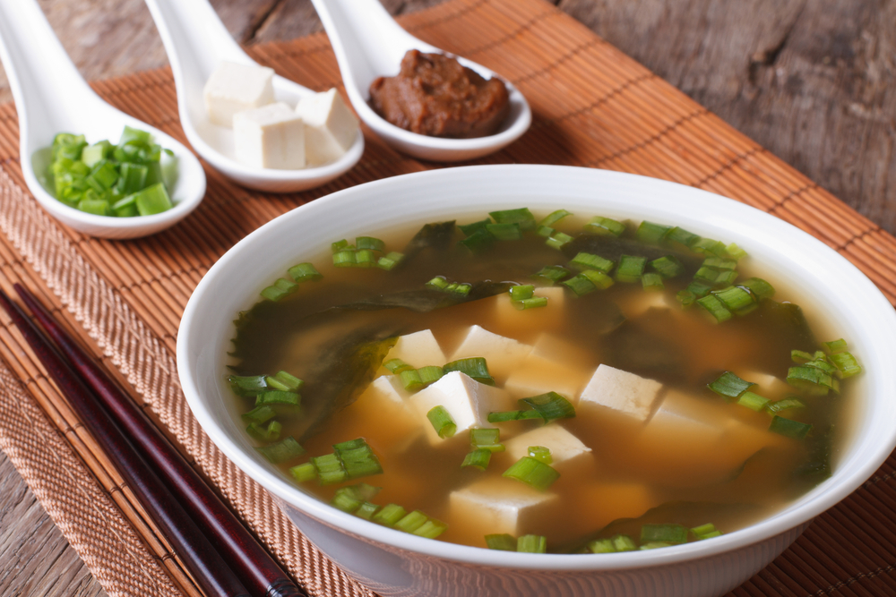 Japanese miso soup in a white bowl and ingredients close-up. Hor