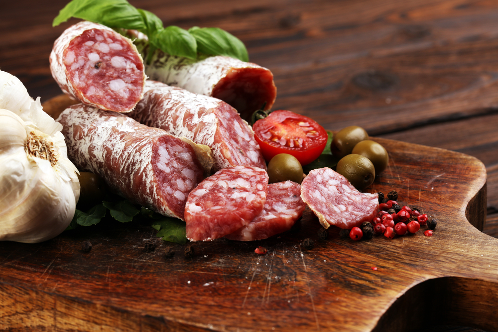 thinly sliced salami on a wooden texture on the background. salami cut